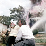 Paris, Texas fire chief Steve Bergin, right, assists firefighters in battling a house fire. The house, which had just been fully restored by its owner, was a complete loss.